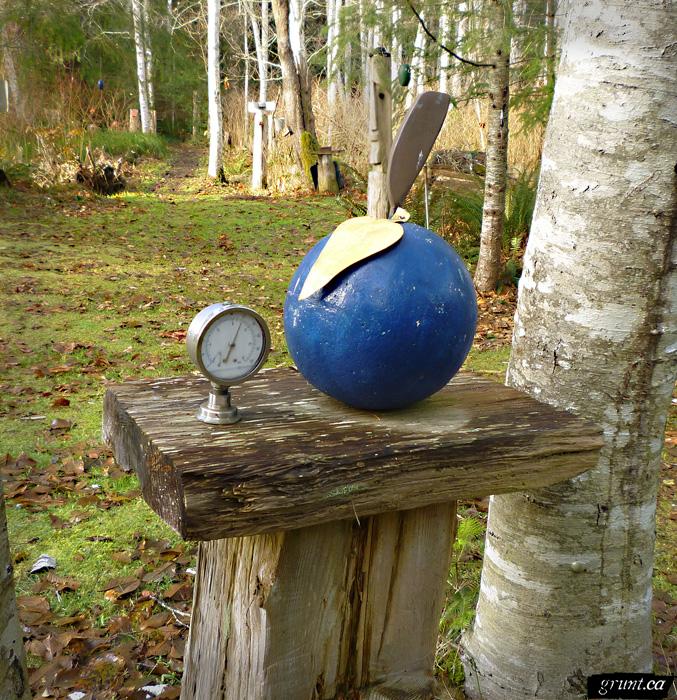 2011 12 Sculpture Yard Work George Sawchuck blue sphere with spade and pressure guage atop a wood plank